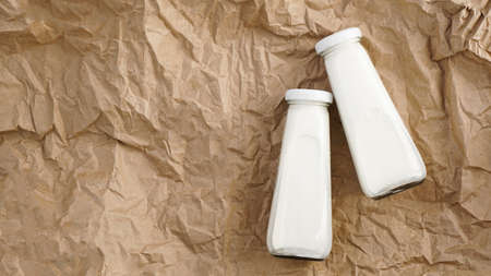 Organic cow milk in glass bottles. Two bottles of milk on crumpled craft paperの写真素材