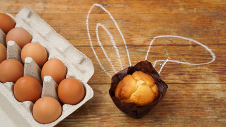 Homemade muffin with painted rabbit ears. Muffin and eggs on a wooden
