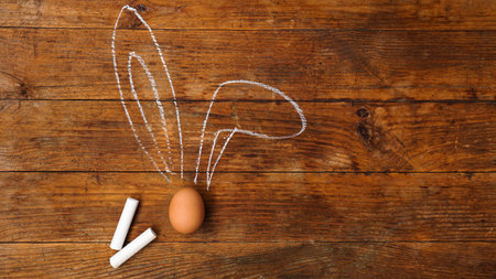 Egg on a wooden background. Chalk-drawn ears. Top view and place for text