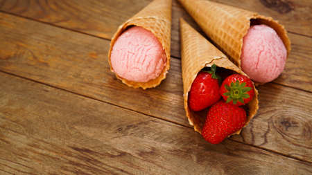 Strawberry ice cream in a waffle cone. Red berries and ice cream ballsの写真素材