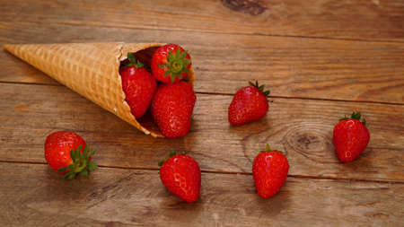 Ice cream cone with strawberries on a wooden backgroundの写真素材