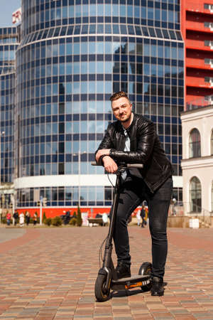 Innovative transport. Glad optimistic guy leaning on electric scooterの写真素材