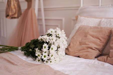 A bouquet of daisies on a bed in a bedroom - Scandinavian styleの写真素材
