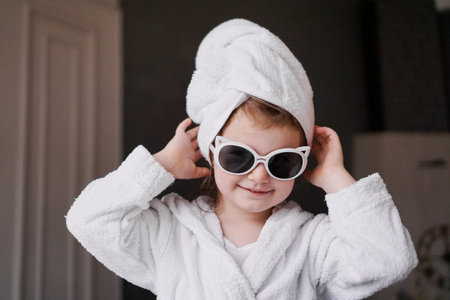 Little girl in a bathrobe and towel, sunglasses. Girl after shower