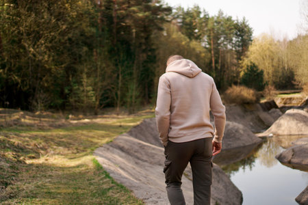 A man walks through the woods next to a rowing canal or mountain river
