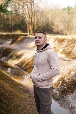 A young man in a comfortable suit walks through the forest by the river.の写真素材