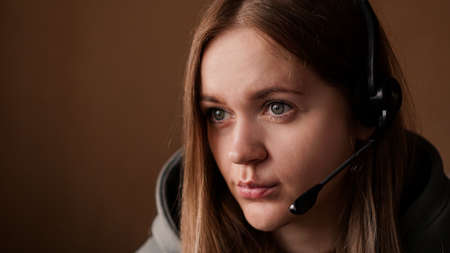 Portrait of a young girl in a hoodie and with a headset. Call center workerの写真素材