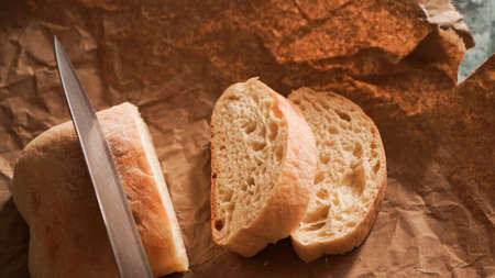 The chef slices the ciabatta with a knife. Ciabatta slices on craft paperの写真素材