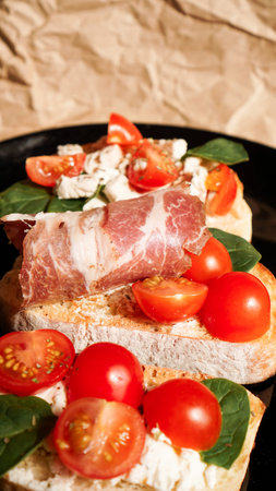 Three bruschetta on a black plate on craft paper. Vertical photo