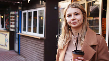 Young blonde with a cup of coffee. Woman at the food court. Lifestyle photo. Beautiful woman drinking coffeeの写真素材