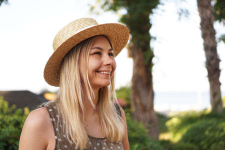 Portrait of a young blonde in a hat on a tropical background. Sunny light and bright colors.の写真素材