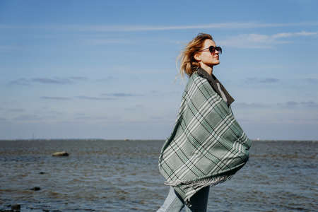 Young woman in sunglasses wrapped in a scarf, autumn on the Gulf of Finland, St. Petersburgの写真素材