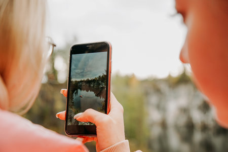 A woman photographs on her phone a canyon in the Ruskeala mountain park in Karelia, Russia. Nature photoの写真素材