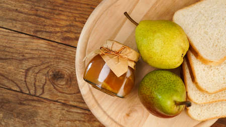 Jar of tasty pear jam with bread and fresh pear fruit on wooden table. Top view. Homemade marmalade, confiture in a glass jarの写真素材