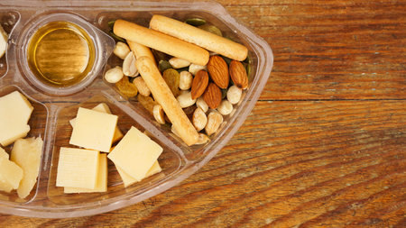 Set of food in a plastic container. Cheese plate for a picnic on a wooden background. Various...