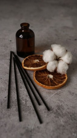 Transparent bottle of aroma diffuser. Parfum for home with cotton flowers, orange fruit. Trending concept, natural materials. Perfume making trainingの写真素材