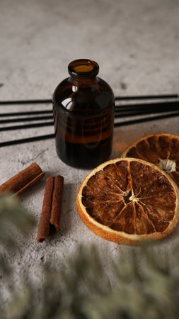 Citrus reed diffuser with cinnamon, dry orange and fir tree branches. Parfum for home. Trending concept, natural materials. Vertical photoの写真素材