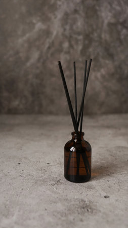 Aromatic reed diffuser bottle with black sticks. Parfum for home. Trending concept. Vertical photo on a marble backgroundの写真素材