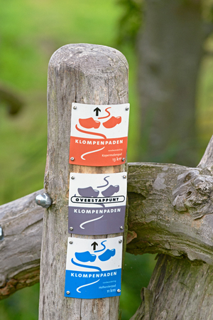 APELDOORN, THE NETHERLANDS, AUGUST 3, 2016 - Direction signs are affixed on a pole marking the hiking trails in rural areas in Gelderland. These trails are called Klompenpaden - Wooden clogs trails.のeditorial素材