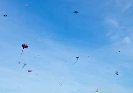 Many beautiful, colorful stunt kites, in the blue sky, high up in the windの写真素材