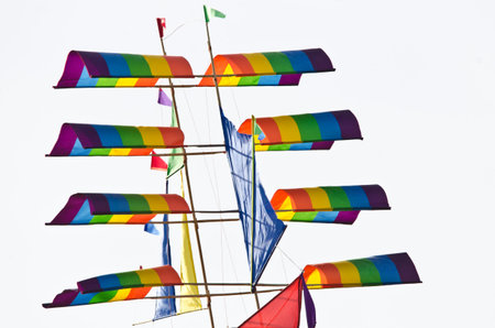 A beautiful, colorful stunt kite, in the blue sky, high up in the wind in the form of a sailing ship