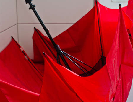 A large red bright umbrella in a white bathtub in a white bathroom for dryingの写真素材