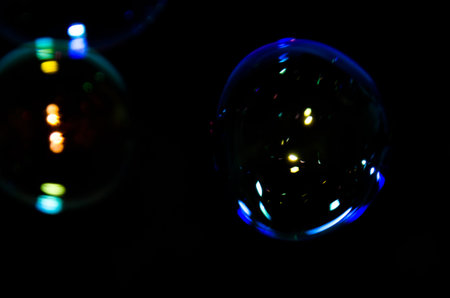 Beautiful bubbles of soap in front of black background, bright and glossy