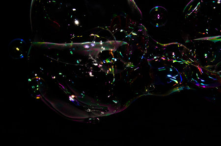 Beautiful bubbles of soap in front of black background, bright and glossy