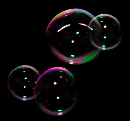 Beautiful bubbles of soap in front of black background, bright and glossy