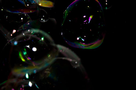 Beautiful bubbles of soap in front of black background, bright and glossy