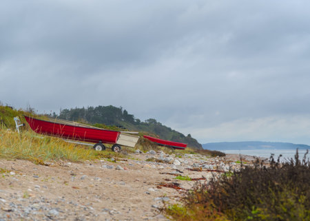 Red boat on the beach in a stormy day, Denmarkの写真素材