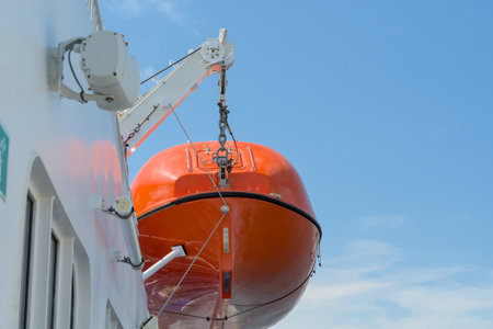Orange lifeboat on the deck of a cruise ship against the blue skyの写真素材