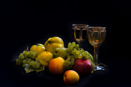 Still life with fruits and wine on a black background. Selective focus. Quinces, apples, pears and grapesの写真素材