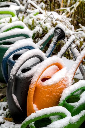 Close up of garden tools, watering cans covered with snow on a sunny winter dayの写真素材