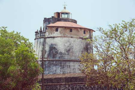 The lighthouse in Fort Aguada on the west coast of India emerging from behind the wall of the fortの写真素材