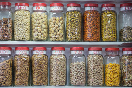 Different kinds of nuts for sale in plastic jarsの写真素材