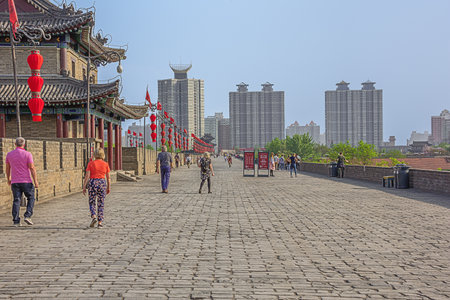 Editorial: XI'AN, SHAANXI, CHINA, April 11, 2019 - Tourists walking on the city wall of Xi'an with modern buildings to the rightのeditorial素材