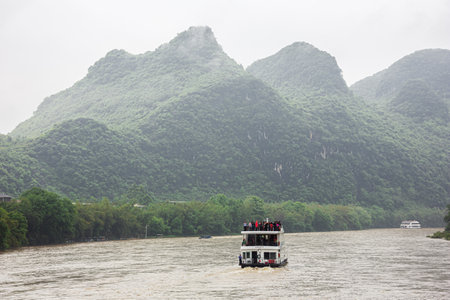 Editorial: GUILIN, GUANGXI, CHINA, April 19, 2019 - Following a river boat navigating on the Li River near Guilinのeditorial素材