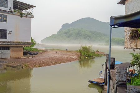 Editorial: DAXUZHEN, GUANGXI, CHINA, April 21, 2019 - Houses overlooking a hazy bank of the Li River in the old town of Daxuzhenのeditorial素材