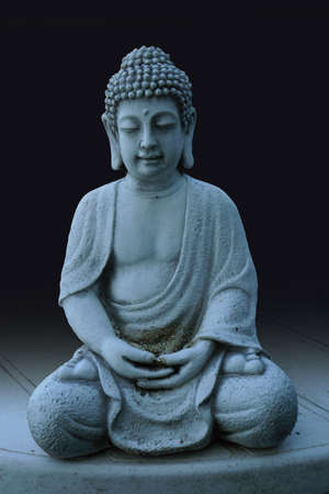 Meditating buddha statue on table shot in studioの写真素材