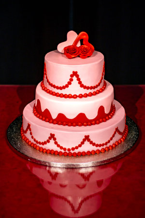 Elegant pink wedding cake decorated with red and pink roses and heartsの写真素材