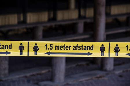 Overloon, Netherlands - May 15, 2020: Attention line (written in dutch) before store to keep social distancing. Social distancing is deliberately increasing the physical space between people to avoid spreading illnessの写真素材