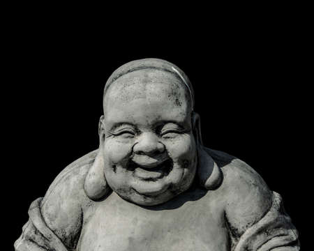 Portrait of a laughing buddha statue, islated on black background. Sign for peace and wisdomの写真素材