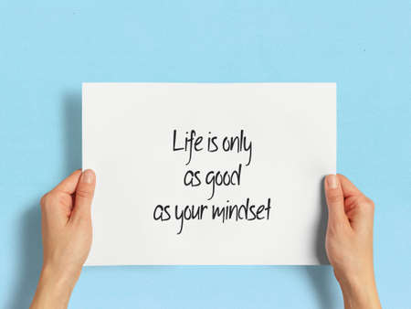 Hand holding papers a4 size with a quote about the meaning of lifeの写真素材