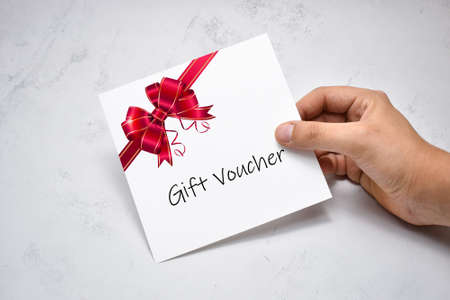 Hand Giving Gift Voucher Card. Holding Prepaid Couponの写真素材
