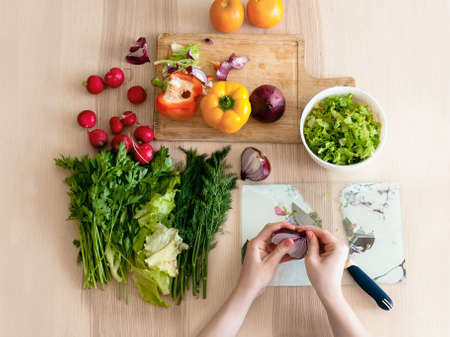 The girl sits in the kitchen and preparing a salad, cutting bow. Flat lay.の写真素材