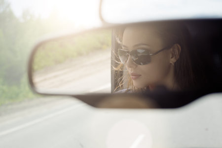 Reflection of a beautiful girl in the car mirror.の写真素材