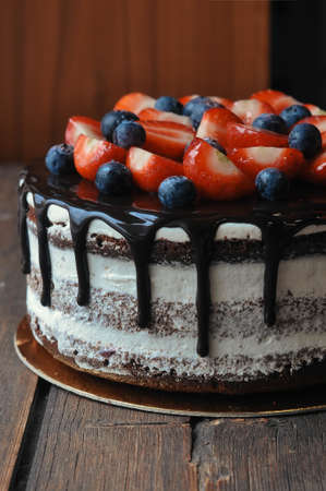 Cake decorated with blueberries and strawberries lying on the table, close-up photoの写真素材