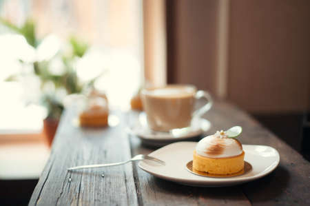 On the wooden table there is a saucer with cake, fork and coffeeの写真素材