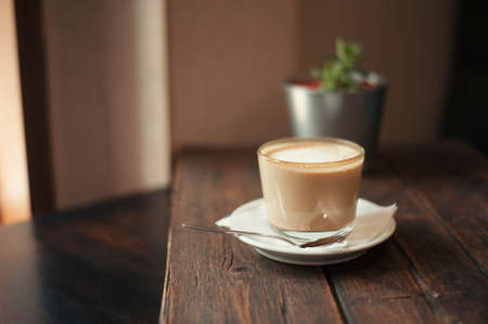 Delicious coffee drink and saucer are on a wooden table in the cafeの写真素材